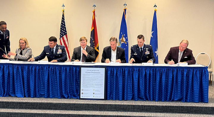 Leaders seated at a table signing a proclamation