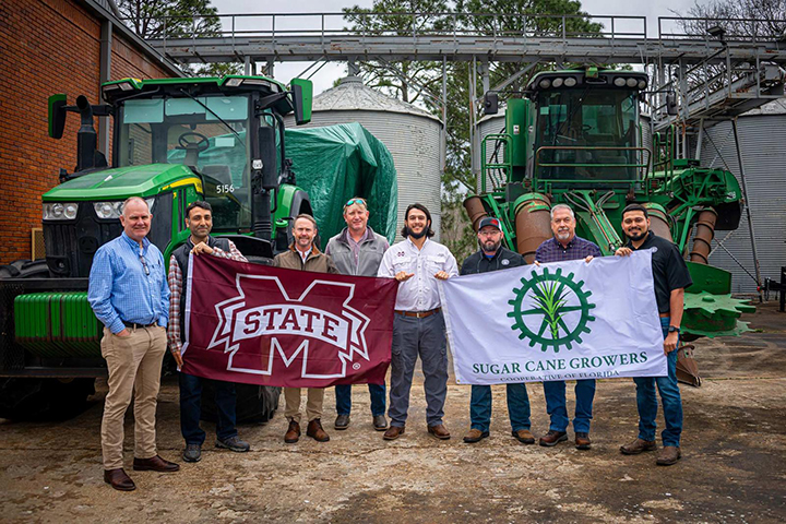 Officials holding flags in front of farm equipment